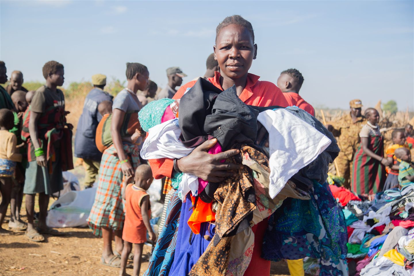 A woman holding donated clothes at an outdoor community clothing distribution in South Sudan